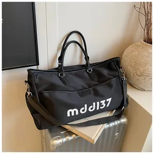 Close-up of black travel bag with dual handles and logo text on silver suitcase