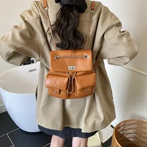 Brown faux leather backpack with metal chains, front pockets and minimalist casual design