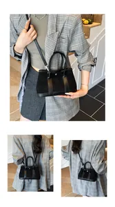 Detail of black trapezoid tote bag showing suede and leather texture with metal buckle
