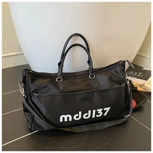 Detail of black travel bag showing mddl37 print, leather handles and zip pocket
