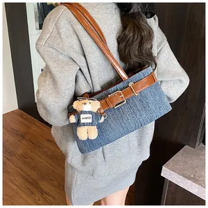 Detailansicht der Denim-Achseltasche mit Lederbesatz und süßem Teddybär-Anhänger