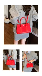 Detail of red suede tote bag showing leather handles and detachable crossbody strap