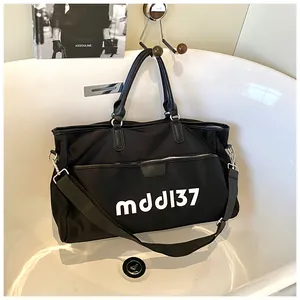 Close-up of black Oxford cloth travel bag with leather handles in a minimal setting