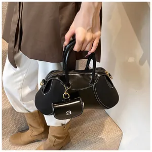 Dettaglio borsa nera lucida con cuciture bianche a contrasto e mini astuccio coordinato