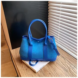 Detail of royal blue tote bag featuring suede texture and adjustable shoulder strap