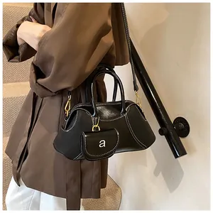 Dettaglio borsa vintage in pelle nera con cuciture bianche e mini custodia decorativa