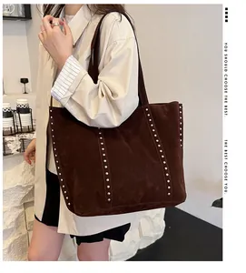 Sac cabas en daim marron avec rivets argentés présenté dans un décor de café élégant