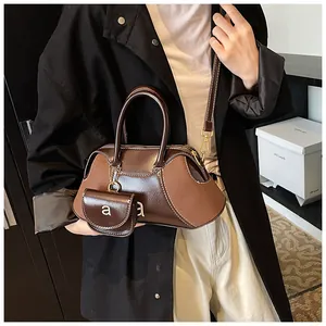 Dettaglio della borsa a mano in pelle marrone scuro con mini portamonete e finiture dorate