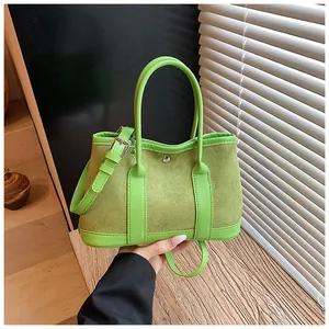 Detail of green tote bag with suede contrast panels and adjustable shoulder strap