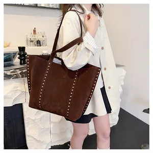 Détail d'un sac cabas marron foncé avec des rivets argentés sur matière mate