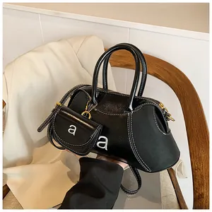 Dettaglio della borsa Boston in pelle nera con cuciture bianche, hardware oro e ciondolo