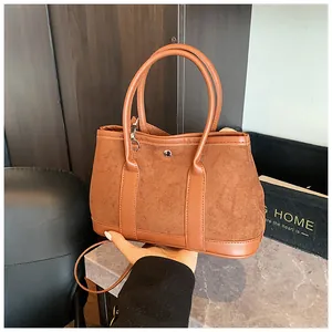 Detailed view of caramel suede tote bag with metal ring handles and stitch detailing