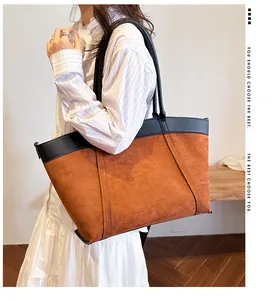Detalle del bolso tote grande de ante marrón con asas de cuero negro y textura