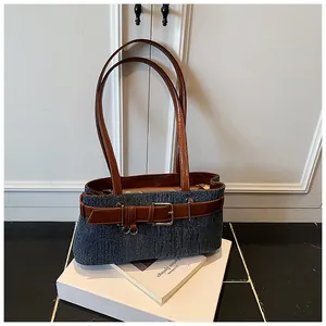 Nahaufnahme der blauen Denim-Baguette-Tasche mit braunem Ledergürtel und Metallschnalle