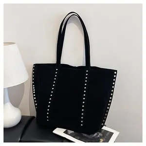 Détail d'un sac cabas noir en nylon avec clous argentés et bandoulières robustes