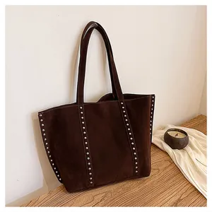 Détails des rivets en métal argenté et coutures blanches sur un sac cabas marron