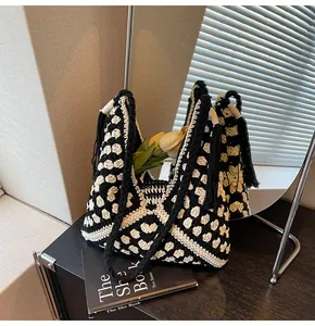 Detail of handmade crochet tote bag with black and white floral patterns and long tassels