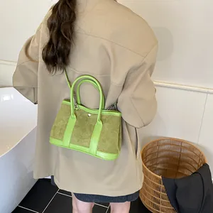 Green color-block tote bag made of suede and leather, worn as a stylish shoulder bag