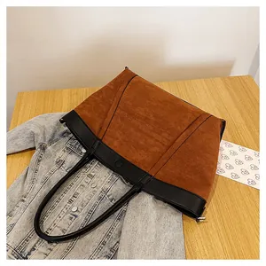 Vista detallada del bolso tote grande de ante marrón con detalles en cuero negro