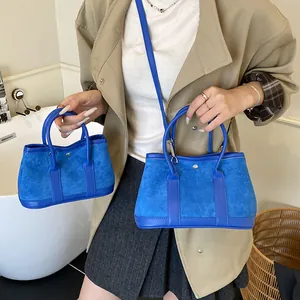 Bright blue contrast leather tote bag in two sizes shown in an indoor lifestyle setting