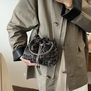 Chic leopard print bucket bag with silver chain strap worn over a khaki trench coat