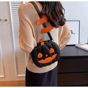 Detail view of pumpkin-shaped crossbody bag featuring bat charms and orange face stitching