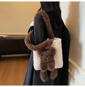Model wearing a fuzzy cream fleece tote bag featuring a cute brown 3D teddy bear charm