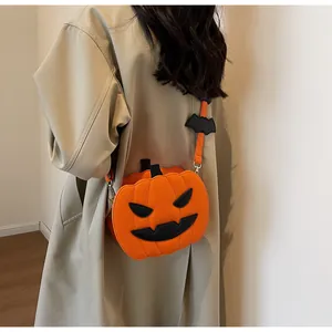Close-up of pumpkin crossbody bag featuring a black bat charm and gold-tone metal hardware