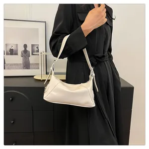Close-up of cream PU leather shoulder bag with fine strap and metallic buckle on model