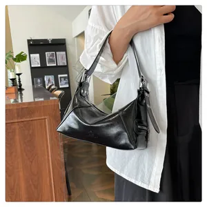 Detail of glossy black leather underarm bag featuring silver hardware and side zipper