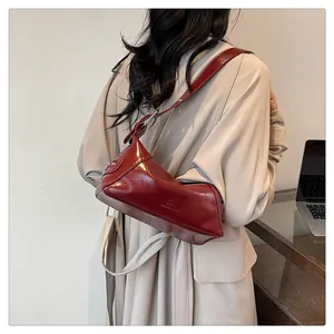 Detail of deep red glossy shoulder bag with embossed logo and silver buckle adjustment