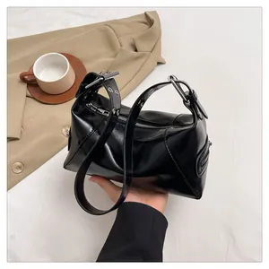Detail of black glossy leather shoulder bag with silver eyelets and adjustable strap