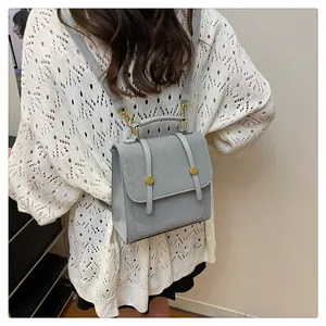 Detail eines hellgrauen multifunktionalen Lederrucksacks mit goldenen Schnallen an einem Model
