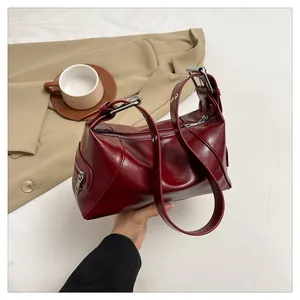 Detail of burgundy glossy shoulder bag with silver metal zipper and adjustable strap