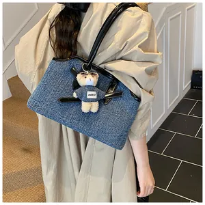 Detail der blauen Denim-Tragetasche mit Lederbesatz und kreativem Teddybär-Anhänger