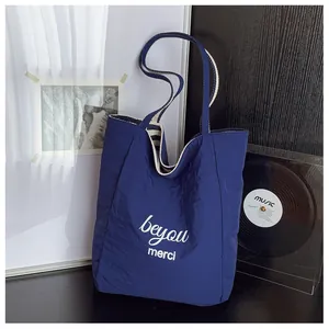 Dettaglio della borsa tote in tela blu navy con testo merci bianco e fodera a righe