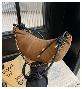 Detail of brown suede crescent bag featuring quilted segments and gold chain strap