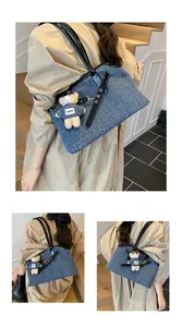 Detail der blauen Denim-Tasche mit schwarzen Lederriemen und süßem Bären-Schlüsselanhänger