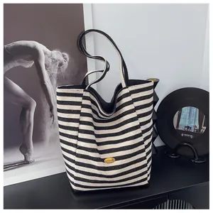 Dettaglio della targhetta in metallo dorato Handmade sulla borsa tote in tela a righe