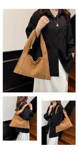 Detail of vintage brown suede hobo bag featuring wide straps with gold rivet eyelets