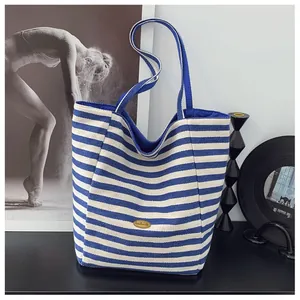 Dettaglio della borsa tote in tela a righe blu e bianche con etichetta dorata handmade