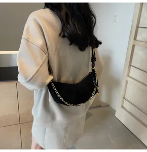 Detail shot of black suede crescent bag with gold chain and leather shoulder strap