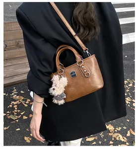 Detailed side view of vintage brown leather bucket bag with cute plush dog pendant