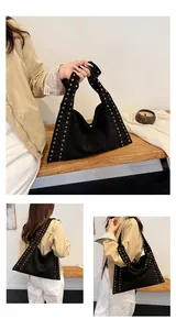 Detail of black suede hobo bag with gold rivet studs and large crescent shape