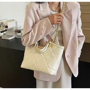 Detail of quilted diamond pattern on beige tote bag with leather-woven chain strap