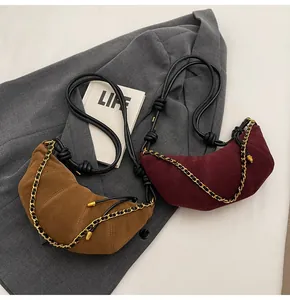 Detail of tan and burgundy matte suede crescent bags with gold chain and leather strap