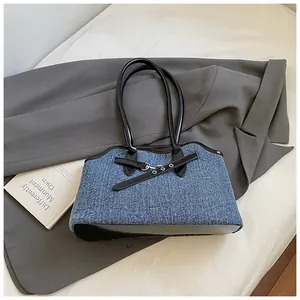 Detail der blauen Denim-Einkaufstasche mit schwarzen Lederakzenten und Silberschnalle