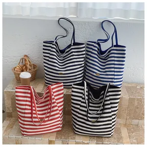 Primo piano di quattro borse tote in tela a righe con etichette in pelle e decorazioni