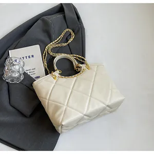 Detail of quilted rhombic tote bag featuring golden chain strap and cream PU leather texture
