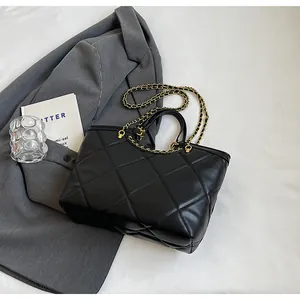 Detail view of black diamond-quilted leather tote with gold chain and leather handles
